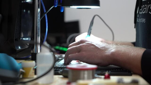 Man fixing up laptop micro soldering under microscope