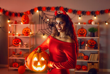 Woman dressed up in Halloween costume of cunning devil. Portrait of happy beautiful girl wearing...