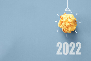 2022 Yellow paper light bulb on blue background, innovative business vision and resolution goal...
