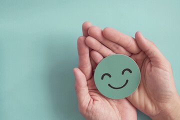 Hands holding green happy smile face paper cut, good feedback rating,positive customer review, experience, satisfaction survey ,mental health assessment, child wellness,world mental health day concept - obrazy, fototapety, plakaty