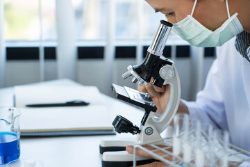 Scientist wear lab coat and protective wear are working with research or doing investigations with test tubes in experiment, Laboratory and development concept