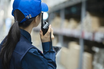 Warehouse worker using walkie-talkie in warehouse