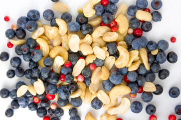 Full frame closeup forest fruit fresh berries colorful assorted large mix in studio on white background. Isolated yummy food pattern of Peanuts, cashews, domesticated, wild blueberries, lingonberries 