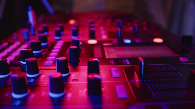 Closeup of digital mixing console and hands adjusting fader. Male hands professional DJ adjust fader slider. Concept modern musical accompaniment of parties in nightclub