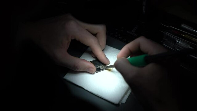 Man microsoldering and repairing boards under light