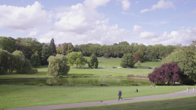 Brussels green skyline time lapse with traffic on road and park with people. Woluwepark, parce de Woluwe