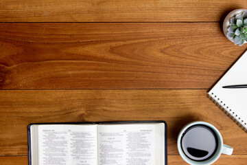 Bible with a cup of coffee on a wooden table.
