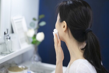 Woman cleaning face with cotton wool	