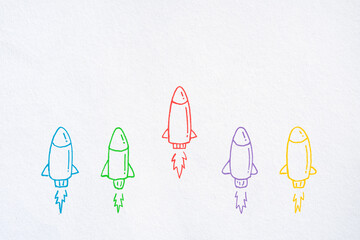 Business competition concept with rocket drawn on white paper background