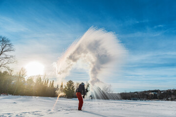 Man throwing boiling hot water freezing mid air. Or rather, the water disperse, vaporize and...