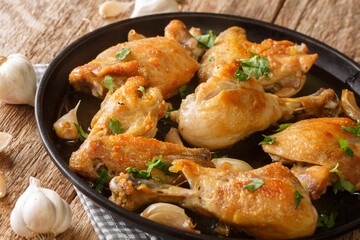 Spanish food chicken fried with garlic, thyme and rosemary close-up in a plate on the table. horizontal