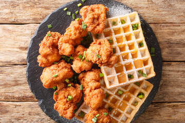 Breaded chicken pieces and crispy waffles with honey sauce close-up on a slate plate on the table. horizontal top view from above