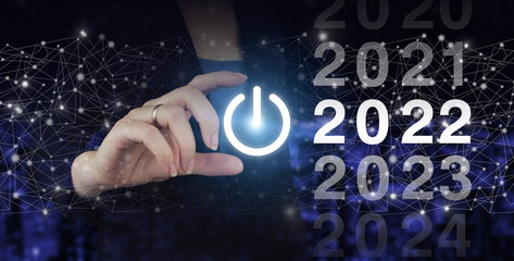 Loading year 2021 to 2022. Start concept. Hand hold digital hologram 2022 sign on city dark blurred background. Concept Start New Year 2022.