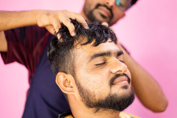 Customer at barber shop enjoying head massage from barber - concept of relaxation and alternative...