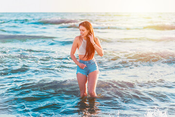 Fototapeta na wymiar Young woman stand in the sea.woman enjoying in sea water .Cheerful young woman having fun on the summer sunset beach.