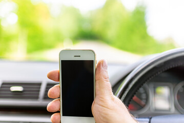 Man hand holding screen smart phone, blur on the road high way forest summer background.copy space,advertisement,banner.