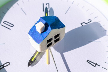 Miniature toy house standing on a clock,Dream house,Real estate concept.Close-up.Selective focus.