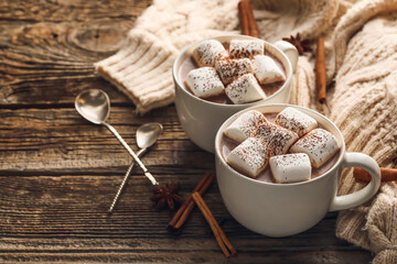 Composition with cups of hot cocoa drink, marshmallows and cinnamon on wooden background