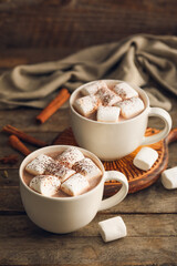 Cups of hot cocoa drink with marshmallows on wooden background
