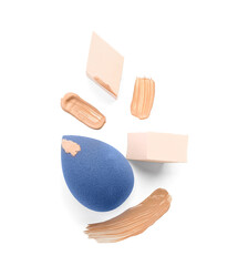 Stylish makeup sponges and foundation samples on white background