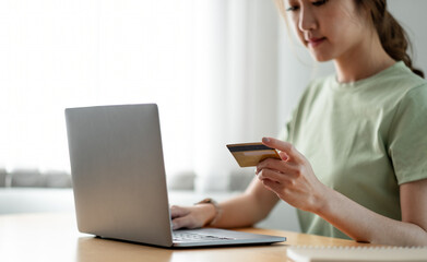 Happy woman doing online shopping at home, woman hand holding credit card and using laptop computer
