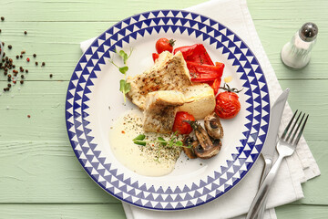 Plate with tasty baked cod fillet, vegetables and mushrooms on color wooden background