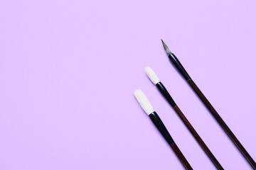 Calligraphic brushes on lilac background