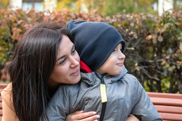 Young mom with her son hug on the bench.
