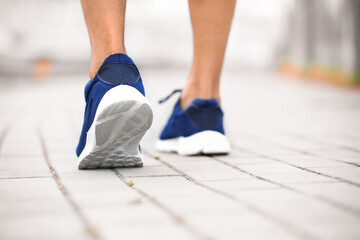 Legs of sporty young man running outdoors, closeup