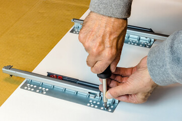 The worker attaches the drawer holders