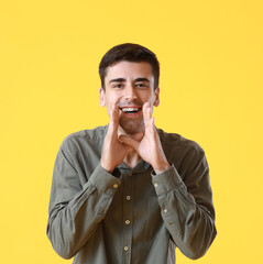 Young gossiping man on yellow background