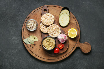 Bowl with tasty baba ghanoush, rice crackers, vegetables and spices on black background