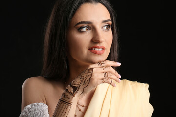 Beautiful Indian woman with henna tattoo on dark background