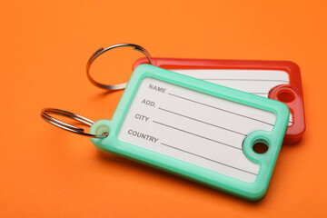 New plastic key tags on orange background, closeup