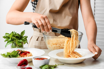 Woman preparing Pasta Puttanesca at kitchen table, closeup