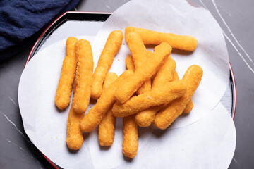 Chicken nuggets sticks in a cup on black background.