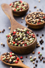Peppercorn mix in a wooden bowl on grey table.