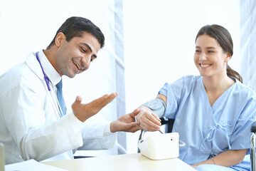 Fototapeta premium Smiling female patient receiving a medical consultation, the doctor is sitting at desk, Medical healthcare concept.