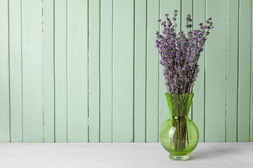 Vase with beautiful lavender flowers on color wooden background