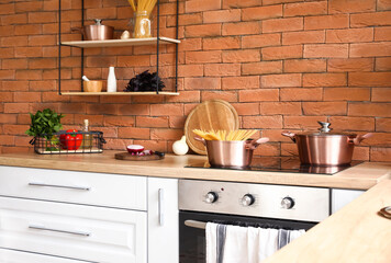 Copper cooking pots with raw spaghetti on stove in modern kitchen