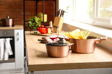 Copper cooking pots with raw pasta on counter in kitchen