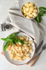 Plate and bowl with tasty gnocchi on light background