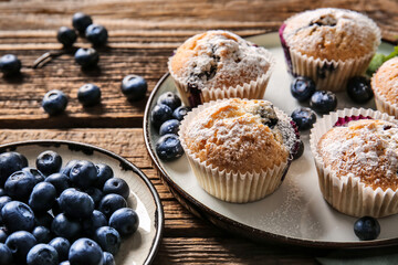 Composition with tasty blueberry muffins and berries on wooden background, closeup
