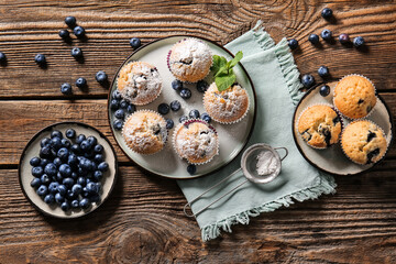 Composition with tasty blueberry muffins and berries on wooden background