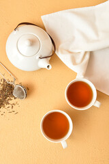 Cups of tasty hojicha green tea and pot on beige background