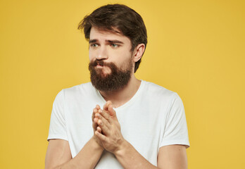 bearded man in a white t-shirt serious look yellow background