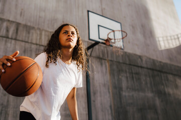 Pre-adolescent girl dribbling ball at sports court