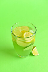 Glass with tasty lemonade on color background