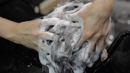 Beautiful young woman in salon washing her hair with salon professional, lifestyle and personal care concept. Close up