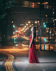 雨の街に立つ赤いドレスの女性